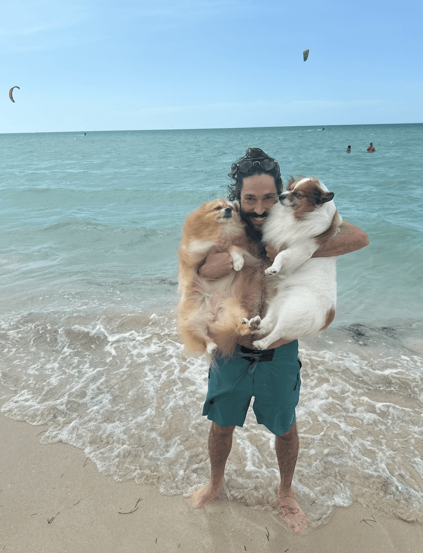 Stephen holding the dogs on the beach with the gulf behind him